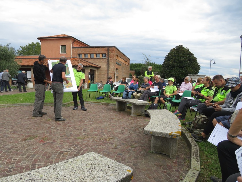 A group of people sitting and listening to three presenters holding a poster. 