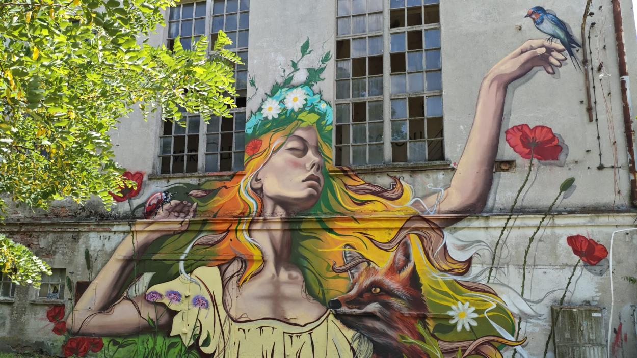 A colorful mural of a woman in a flower crown surrounded by greenery and animals.