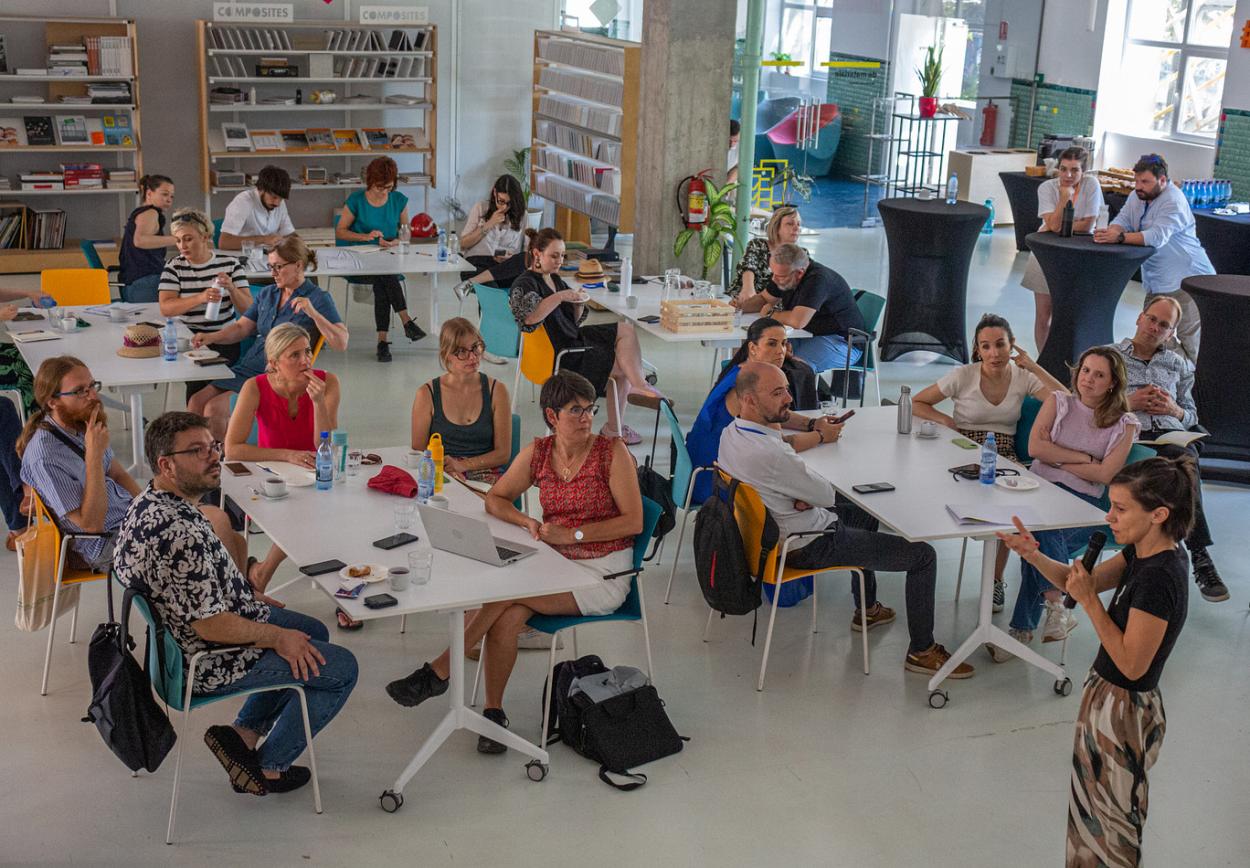People sitting by the tables and listening to the presentation.