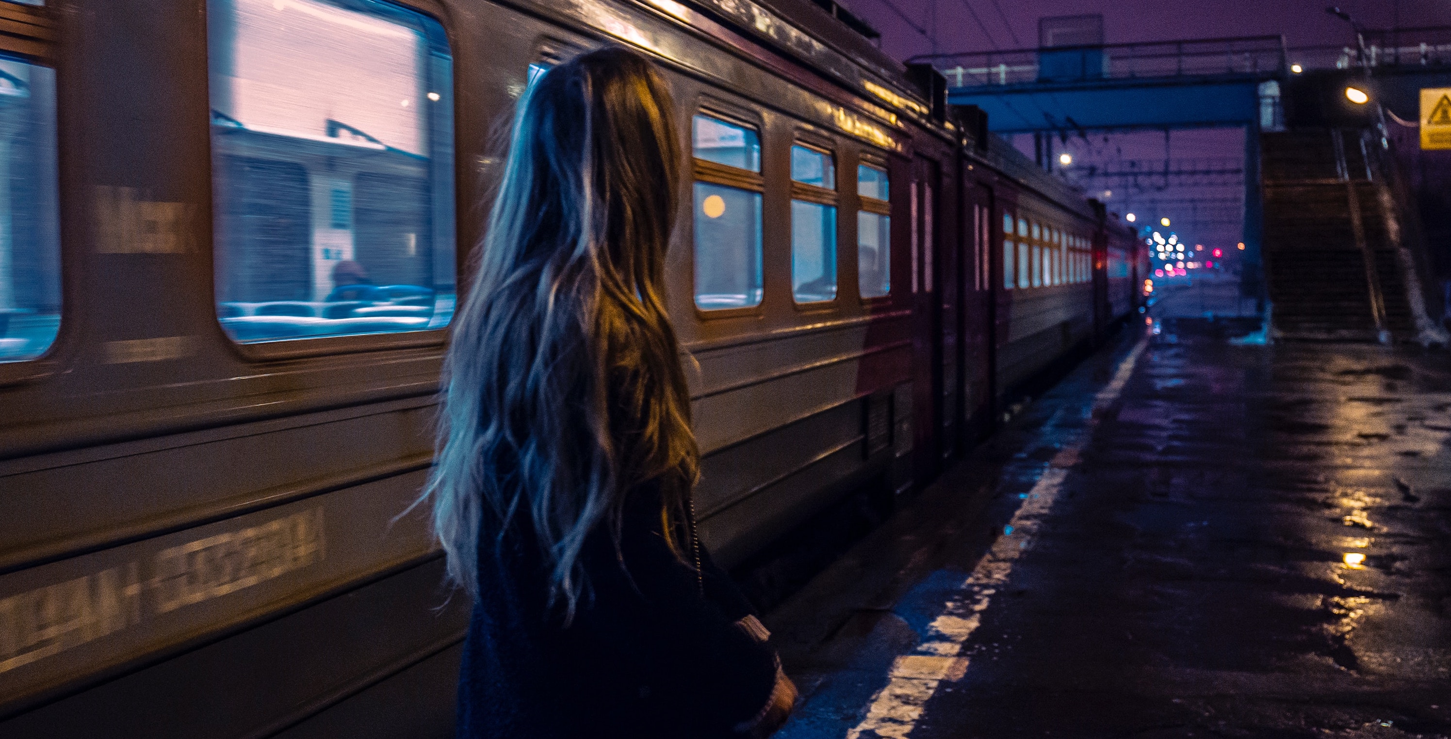A woman standing in front of a train at night.