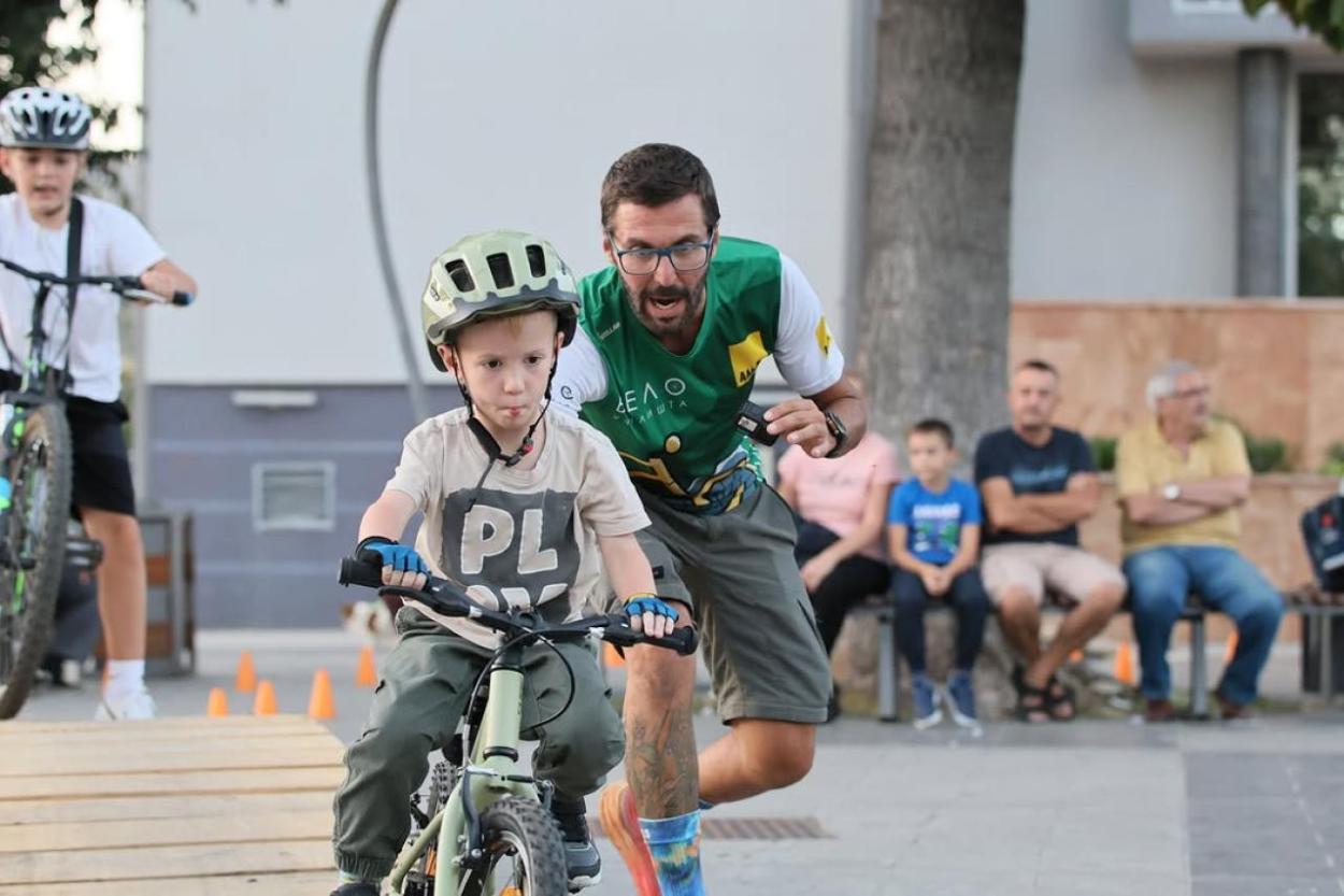 A person pushing a child on a bicycle 