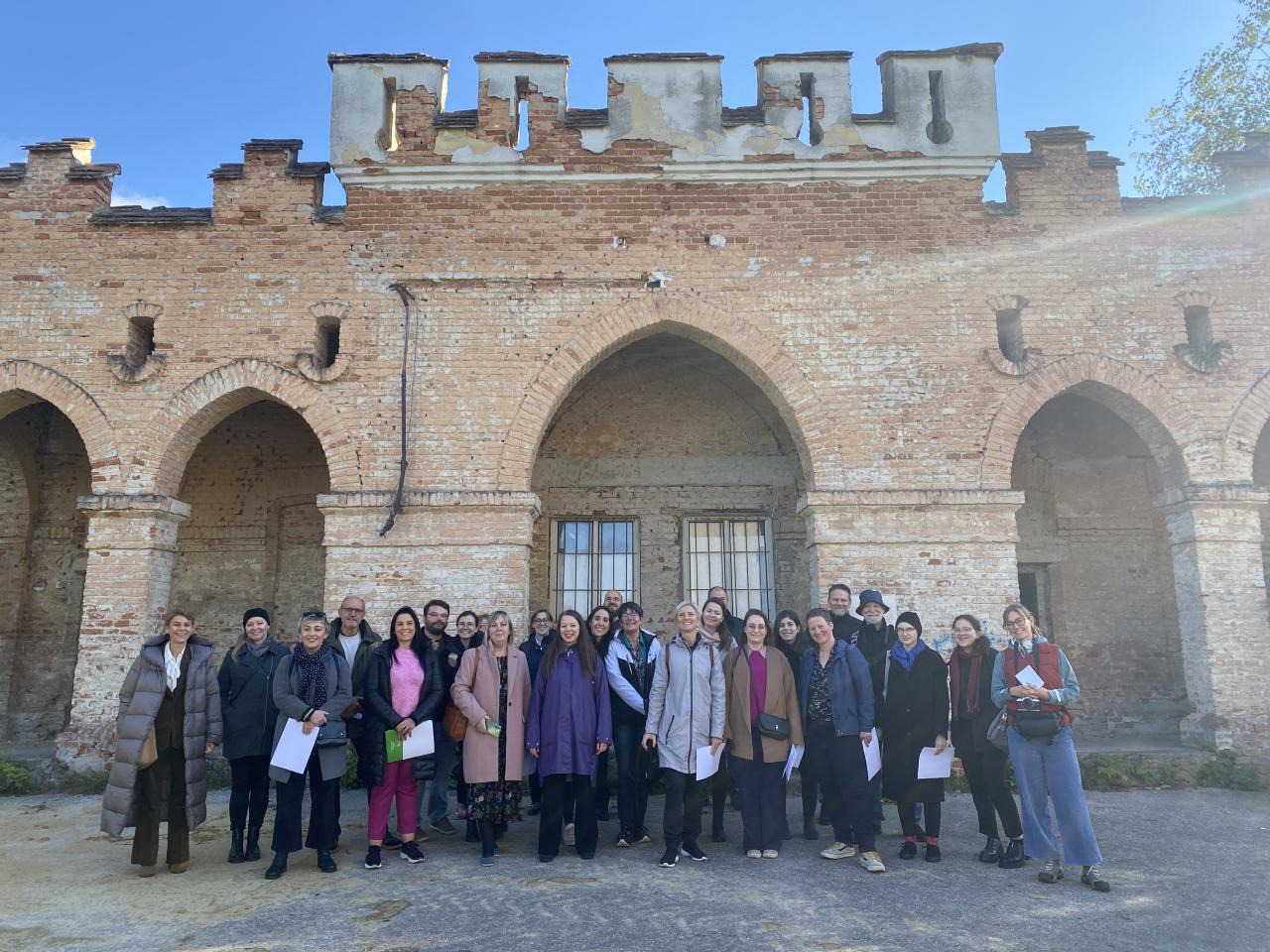 a group of people posing for a picture in from of an old building