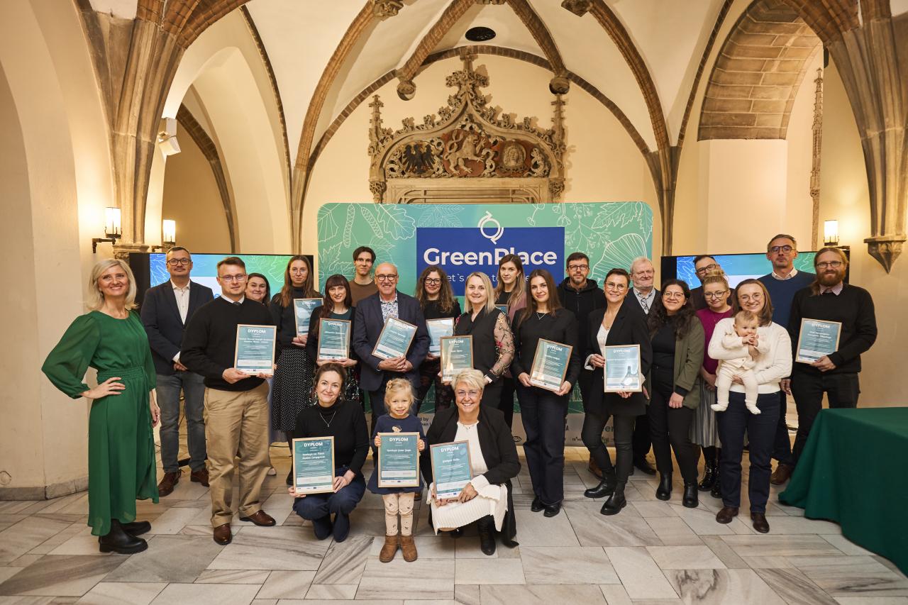 A conference participants posing for the picture in front of GreenPlace backdrop. 