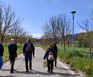 A group of five people walking on a paved pathway in a green urban area. 