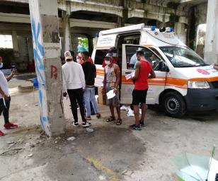 A moment of community healthcare provision in an urban setting, with an ambulance and medical personnel attending to the needs of the local residents.