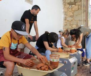  A group of people engaged in a hands-on activity, likely a workshop or community event focused on working with clay or a similar material.