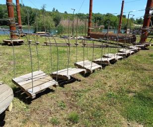 The picture shows a path with wooden playground equipment in a park