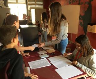 Several people are gathered around a table, engaged in the process of voting or assisting with the voting process.