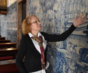 A woman indicating a painting on a wall of a building. 