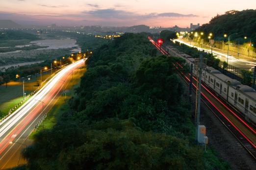 A road next to a train that crosses the tracks.