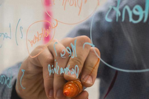 Person writing with a permanent marker on a transparent blackboard