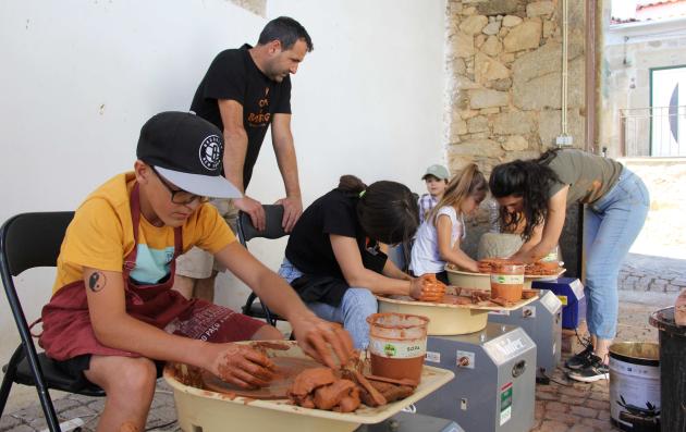  A group of people engaged in a hands-on activity, likely a workshop or community event focused on working with clay or a similar material.