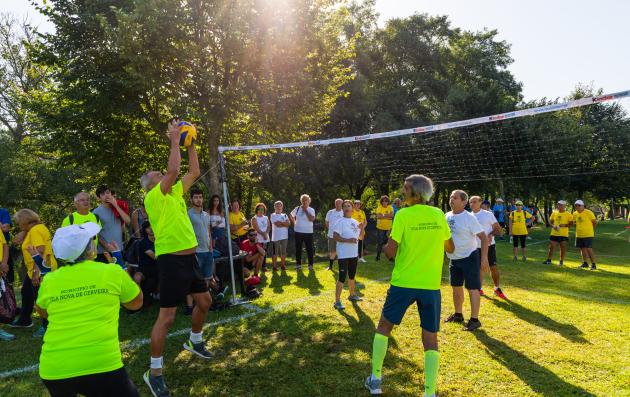 Vibrant scene of a community volleyball game, with players actively engaged in the sport and spectators enjoying the event in a pleasant outdoor environment.