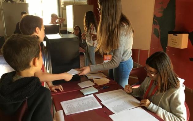 Several people are gathered around a table, engaged in the process of voting or assisting with the voting process.