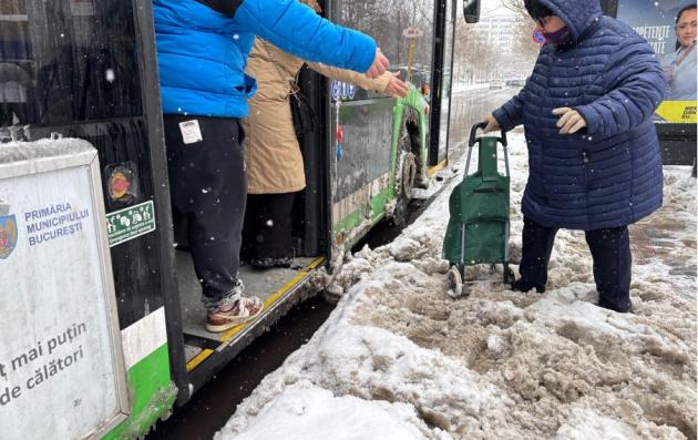 © photo Iris Popescu, 2025. Alt-text: Two people assist an elderly woman with a trolley as she boards a bus, offering their hands to help her navigate a snowy, uncleared bus stop area.