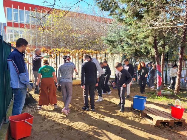 Group of people working on plot of land in front of a school building
