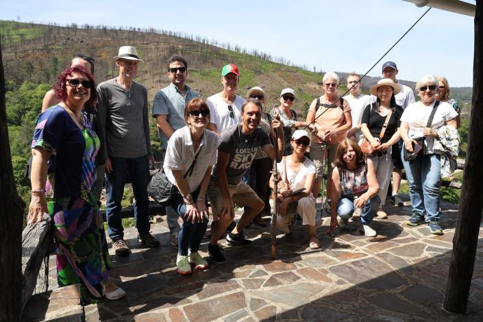 Group of people standing outside on a terrace with mountain backdrop