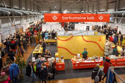 This image depicts a bustling indoor market or fair, likely focused on food and local products.