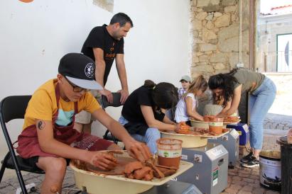  A group of people engaged in a hands-on activity, likely a workshop or community event focused on working with clay or a similar material.