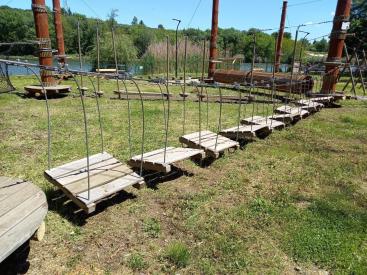 The picture shows a path with wooden playground equipment in a park