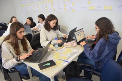 A group of young individuals, likely students, engaged in a collaborative learning or workshop setting. 