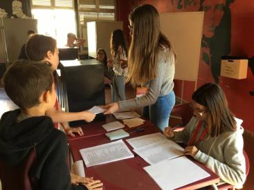 Several people are gathered around a table, engaged in the process of voting or assisting with the voting process.