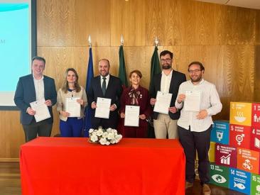 Six representatives from the GreenPlace network stand holding signed commitment documents