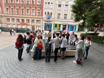 Hallgatói csoport Zágráb főterén a város bronz modellje felett beszélget